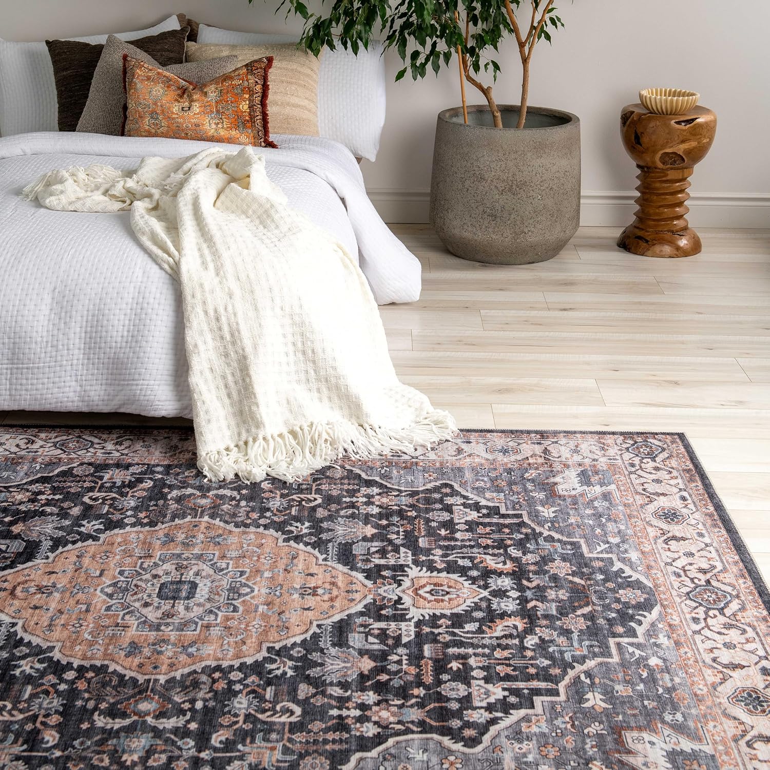 Cozy bedroom with patterned rug and blankets.