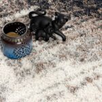 Ceramic candle holder and cat figurine on rug.