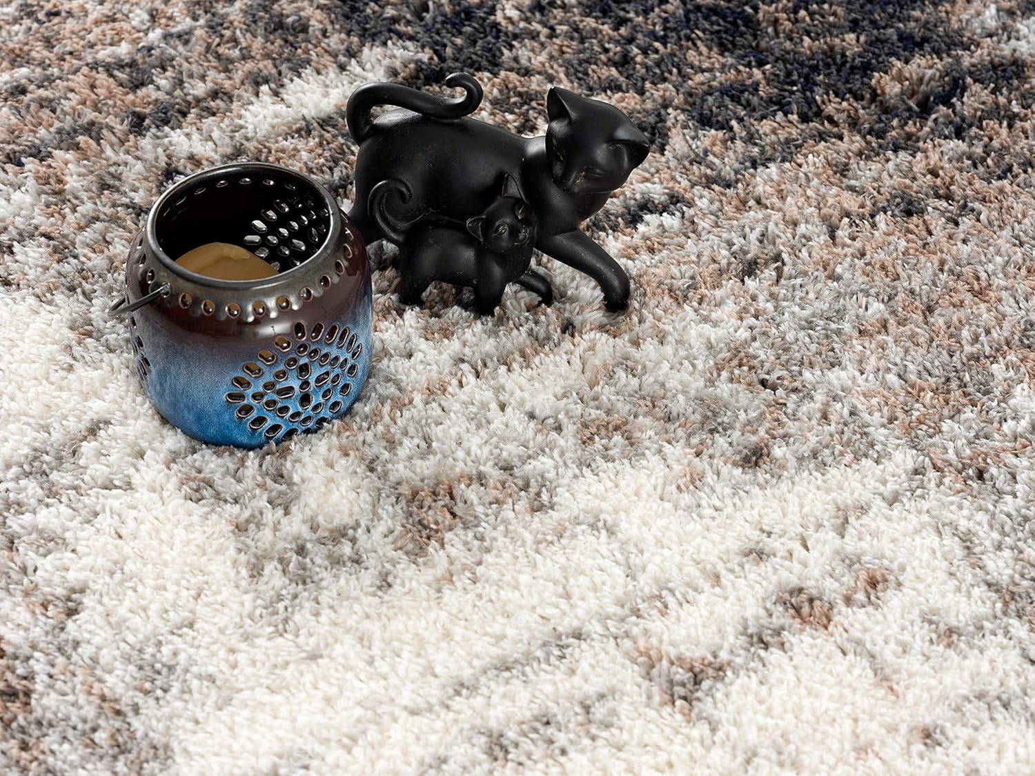 Ceramic candle holder and cat figurine on rug.