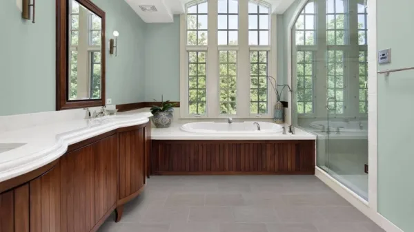 Bathroom with large windows, bathtub, and wooden cabinets.