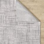 Gray patterned rug on wooden floor background.