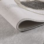 Close-up of folded beige and gray area rug.