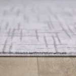 Close-up of white patterned rug on wooden floor.