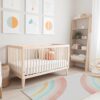 Modern baby nursery with crib and colorful decor.