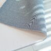 Blue rug corner on light wooden floor.