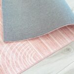 Folded pink and gray rug on wooden floor.