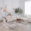 Modern living room with white sofa and abstract rug.