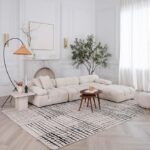 Modern living room with white sofa and abstract rug.