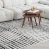 Modern coffee table on striped rug near sofa.