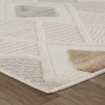 Beige and white geometric patterned rug on wood floor.