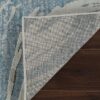 Corner of blue area rug folded on wood floor.