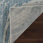 Corner of blue area rug folded on wood floor.
