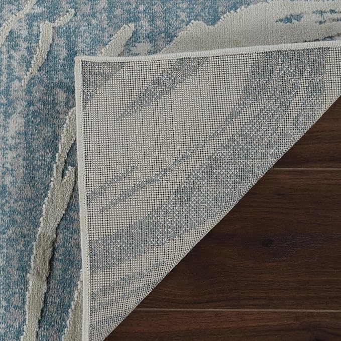 Corner of blue area rug folded on wood floor.
