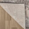 Gray shag rug on wooden floor, corner lifted.