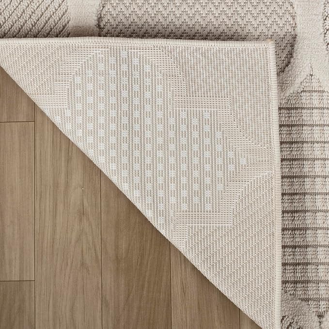 Corner of beige patterned rug on wooden floor.