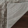 Partially flipped textured rug corner on wooden floor.