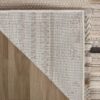 Corner of beige rug on wooden floor
