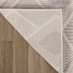 Patterned rug on wooden floor corner view.
