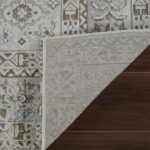 Patterned rug corner lifted on wooden floor.