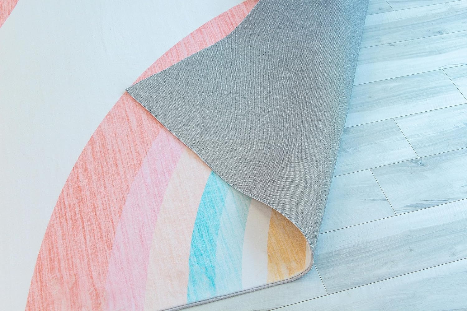 Colorful rug corner on wooden floor.