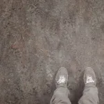 Person wearing gray shoes on brown floor