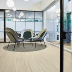 Modern office lounge with chairs and glass partitions.