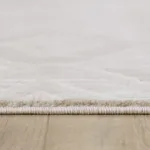 Close-up of white rug on wood floor.