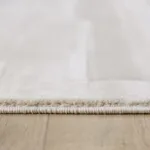 Close-up of beige rug edge on wooden floor