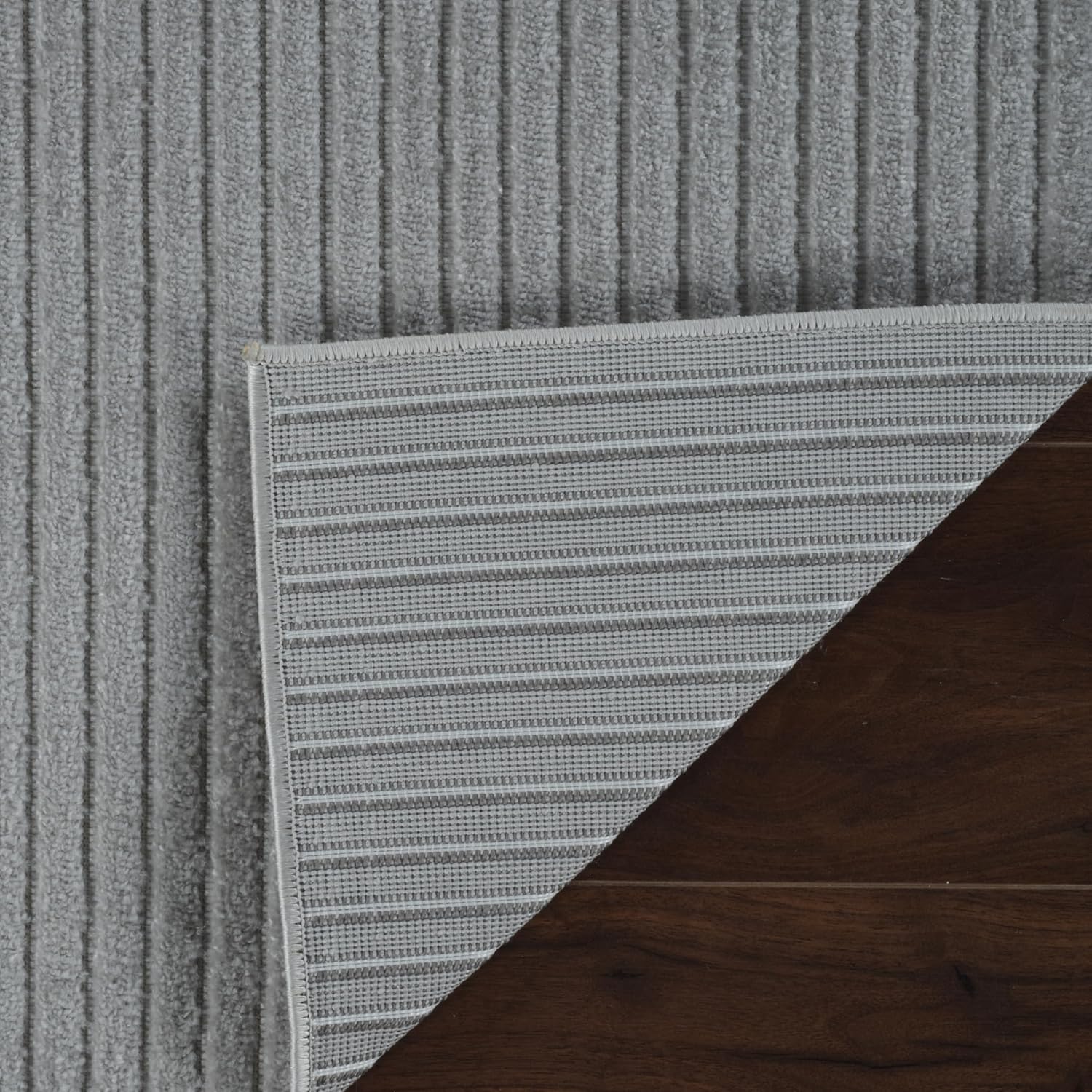 Gray woven rug on dark wood floor.