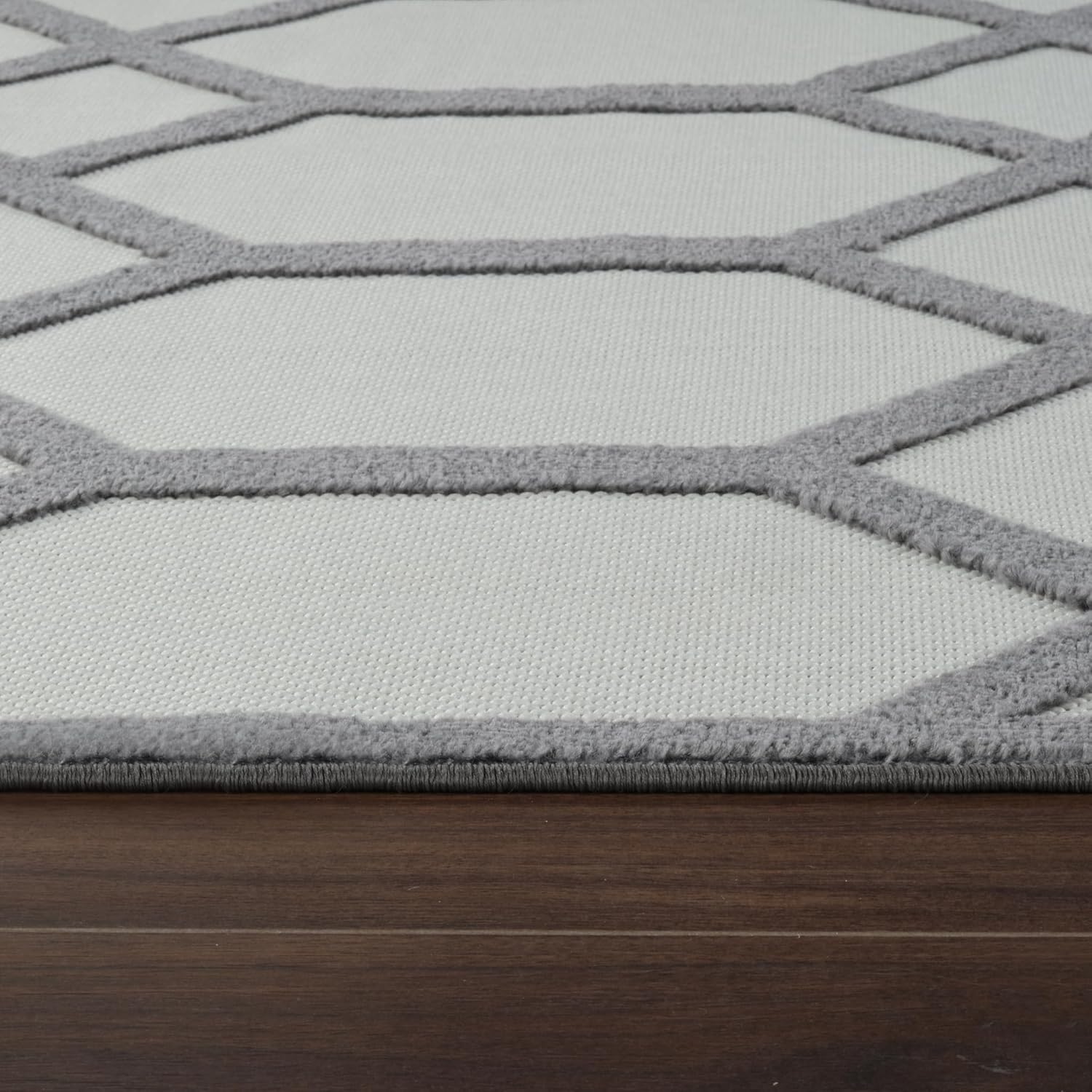 Gray geometric patterned rug on wooden floor.