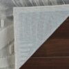 Gray rug corner flipped on wooden floor.