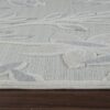 Leaf-patterned rug with textured design on hardwood floor.