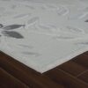 Textured floral area rug on dark wood floor.
