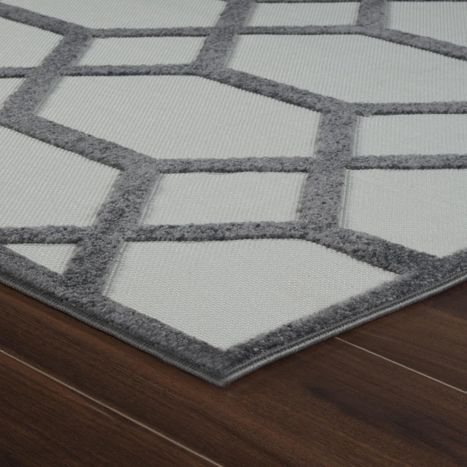 Gray and white geometric rug on wooden floor.