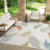 Outdoor patio with patterned rug and seating area.