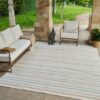 Outdoor patio with striped rug and seating area.