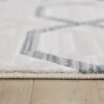 Close-up of a gray geometric-patterned rug on wood floor.