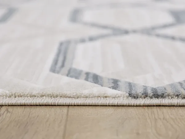 Close-up of a gray geometric-patterned rug on wood floor.