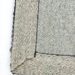 Close-up of textured gray woven rug corner.