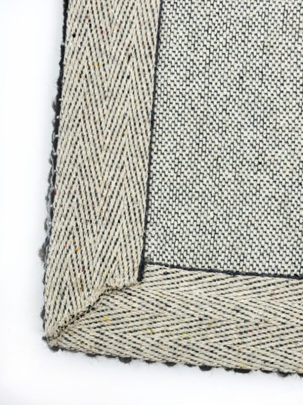 Close-up of textured gray woven rug corner.