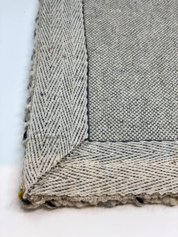 Close-up of woven fabric corner, gray and beige.