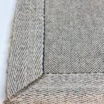 Close-up of woven gray and white rug corner.