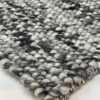 Close-up of textured woven carpet in grayscale.