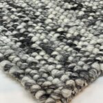 Close-up of textured woven carpet in grayscale.