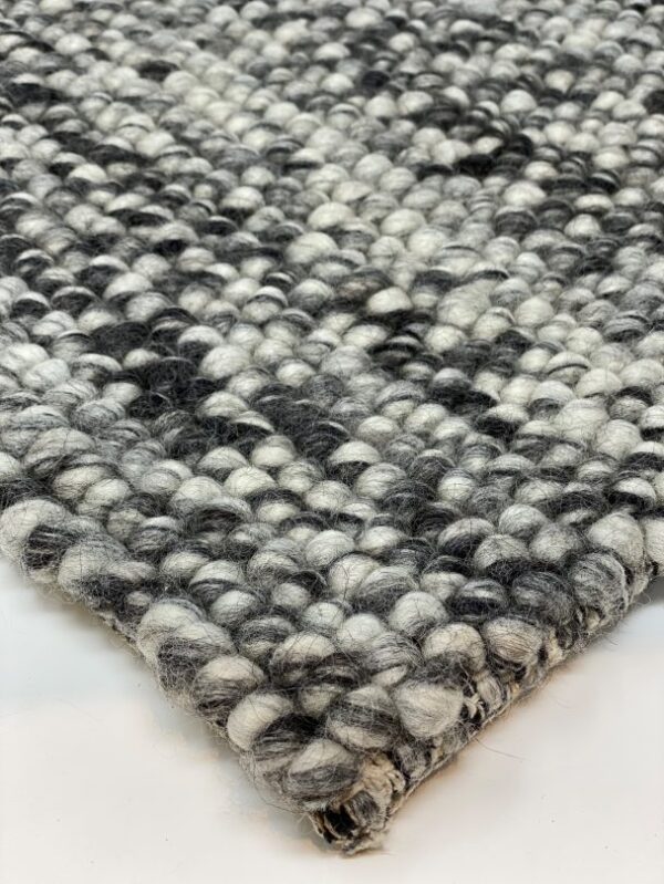 Close-up of textured woven carpet in grayscale.