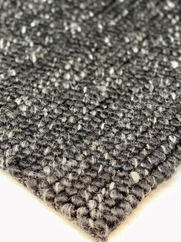 Close-up of woven gray textured rug corner.