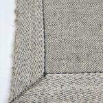 Close-up of woven herringbone rug corner.