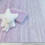 Star and rectangular pillows on purple-striped carpet.