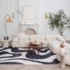 Modern living room with white sofa and abstract rug.