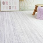 Lilac rug with pillow and stool in room.